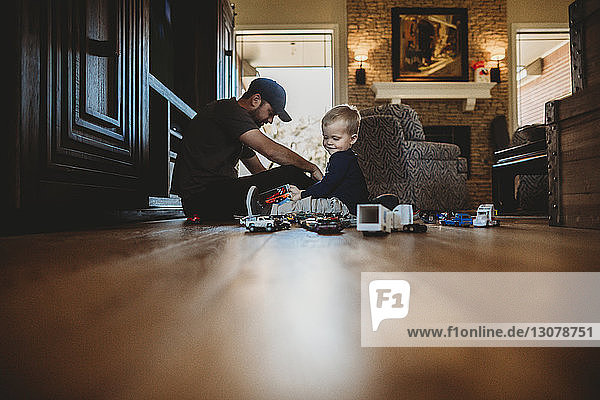 Ebenerdiges Bild von Vater und Sohn  die zu Hause mit Spielzeugautos auf dem Boden spielen