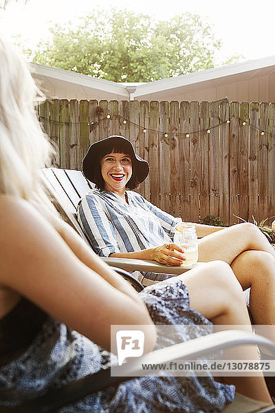Female friends talking while sitting on chairs in yard