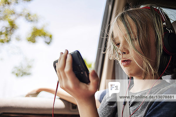 Junge hört Musik mit dem Mobiltelefon  während er im Auto sitzt