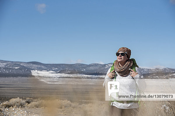 Wanderin mit Rucksack erkundet im Winter Wüste gegen den Himmel