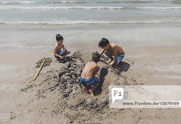 High angle view of shirtless brothers playing on shore at beach