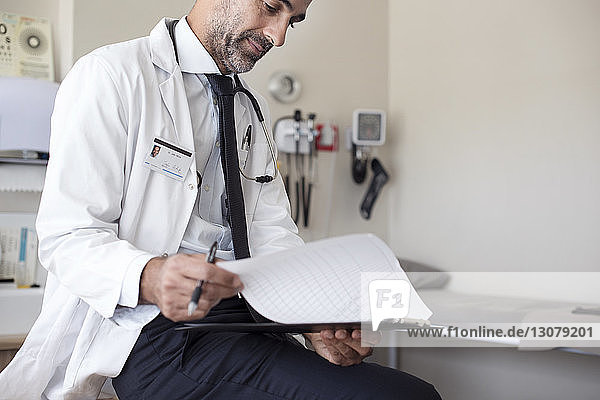 Doctor preparing reports while sitting in hospital