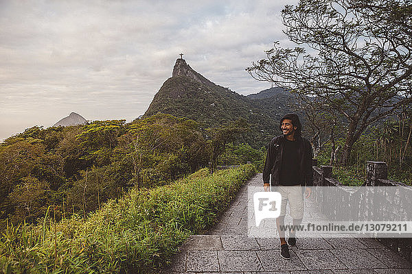 Smiling man moving up on steps against mountain at Rio de Janeiro