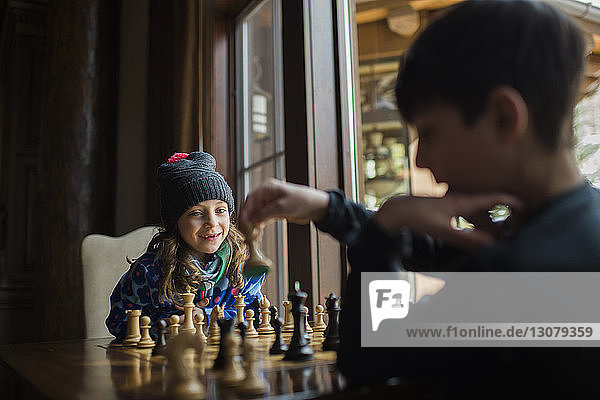 Geschwister spielen zu Hause am Fenster Schach