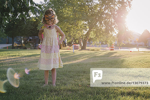 Portrait of girl in eye mask standing on grassy field at park