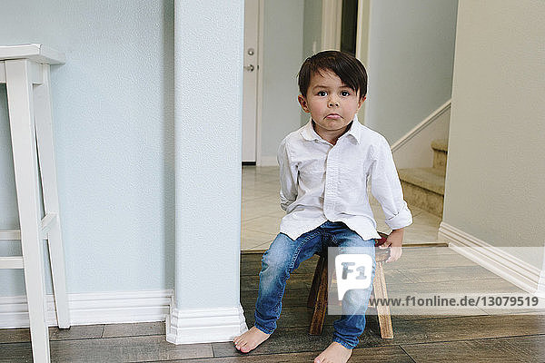 Porträt eines süßen Jungen  der zu Hause auf einem Hocker sitzt