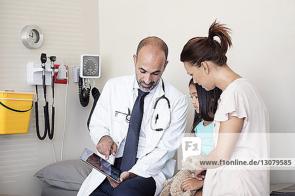Arzt zeigt dem Patienten einen Tablet-Computer  während er im medizinischen Untersuchungsraum sitzt