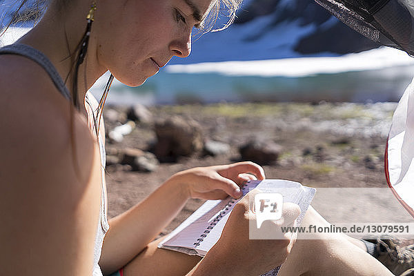 Wanderin schreibt auf Notizblock  während sie auf dem Campingplatz sitzt
