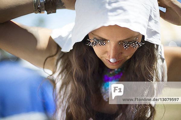 Hochwinkelaufnahme einer Frau mit Gesichtsbemalung und falschen Wimpern bei einer traditionellen Veranstaltung