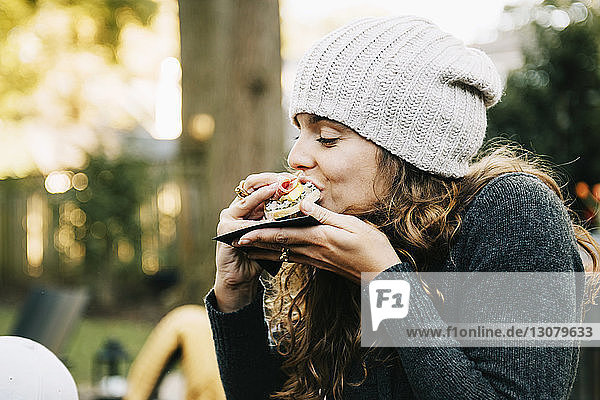 Frau isst Sandwich  während sie im Hinterhof sitzt
