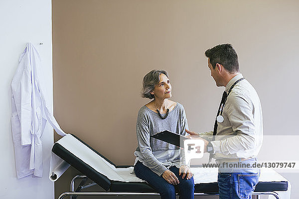 Älterer Patient spricht mit Arzt  während er im Krankenhaus im Bett an der Wand sitzt