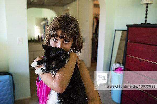 Porträt eines Mädchens  das zu Hause eine Katze trägt
