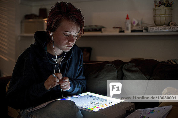 Teenagerin benutzt Tablet-Computer  während sie zu Hause auf dem Sofa sitzt