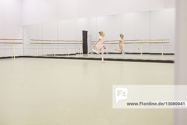 Happy ballet dancer dancing in front of mirror at dance studio