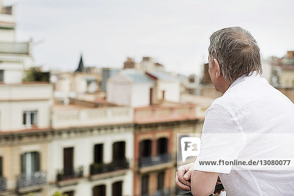 Seitenansicht eines älteren Mannes  der die Stadt von der Terrasse aus betrachtet