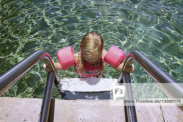Hochwinkelansicht eines Mädchens über eine Leiter im Schwimmbad