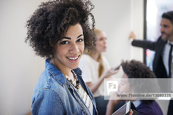Portrait of businesswoman with curly hair while colleagues in background