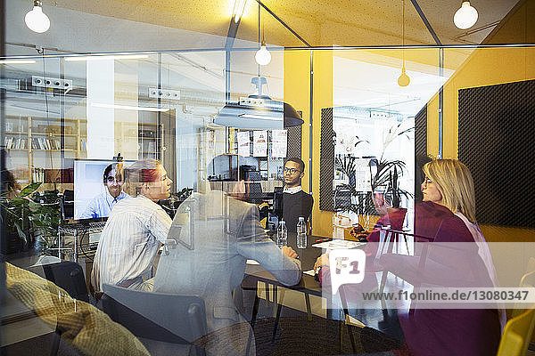Geschäftsleute bei Videokonferenzen bei Besprechungen im Büro durch Glasfenster gesehen