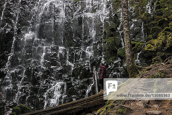 Side view of woman standing by Ramona Falls in forest