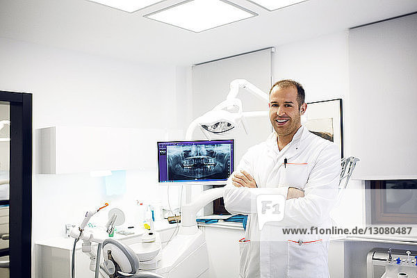 Porträt eines selbstbewussten Zahnarztes  der in der Klinik an der zahnärztlichen Ausrüstung steht