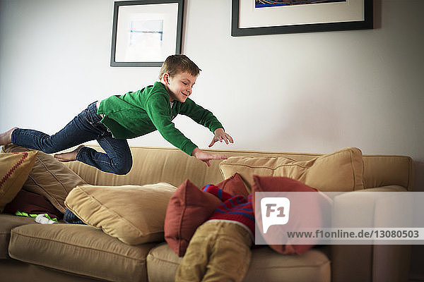 Brothers jumping and playing on sofa at home
