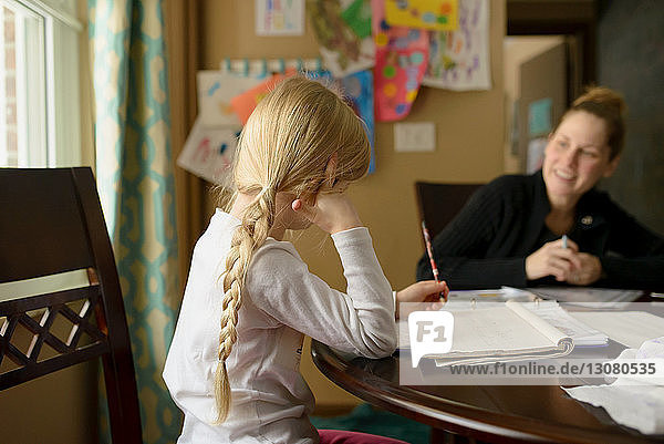 Mädchen lernt  während sie mit der Mutter zu Hause sitzt
