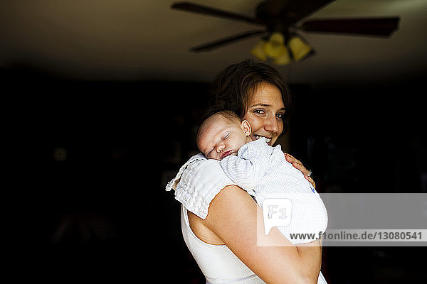 Porträt einer lächelnden Mutter  die ein Mädchen zu Hause trägt