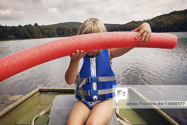 Mädchen hält Nudelschwimmer  während sie im Boot sitzt