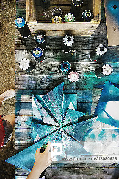 Overhead view of woman spraying paint on art work at studio