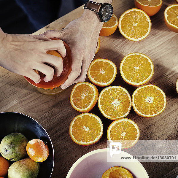 Directly above view of hands squeezing oranges