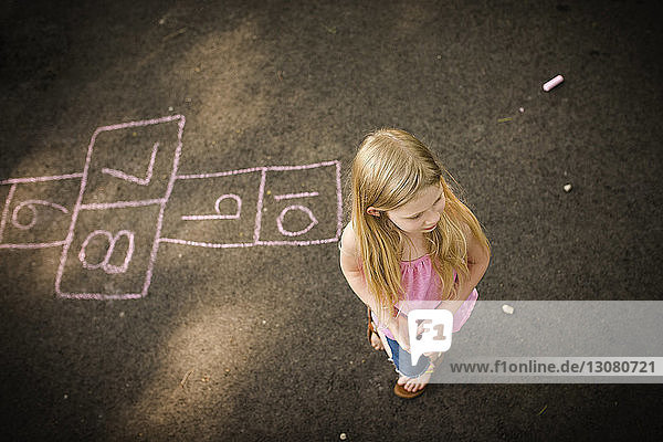High angle view of girl standing by hopscotch game
