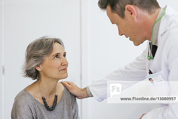 Close-up of doctor comforting senior patient in medical clinic