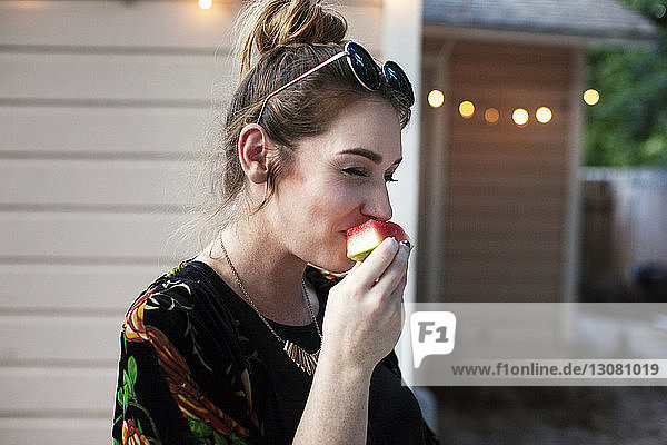 Frau isst Wassermelone im Hof