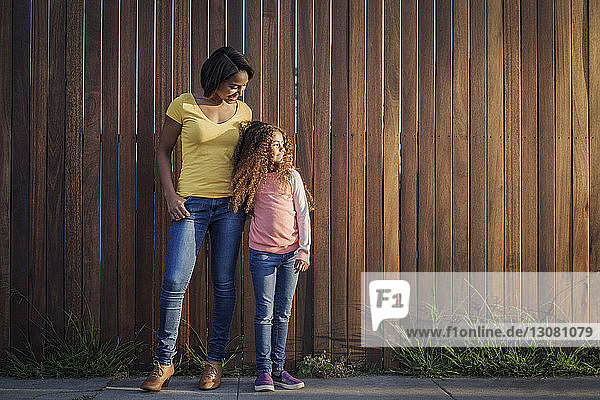 Mutter und Tochter an Holzzaun stehend