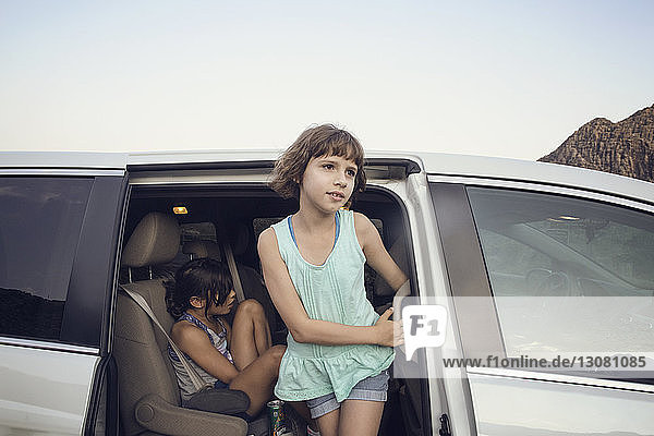 Mädchen schaut weg  während sie an der Autotür steht