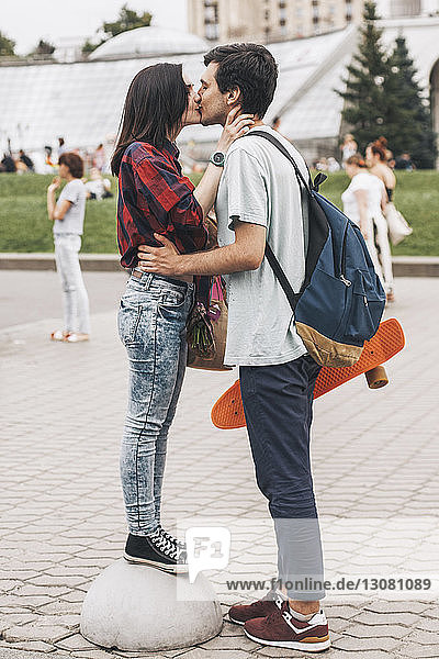 Seitenansicht eines verliebten jungen Paares  das sich in der Stadt auf den Mund küsst