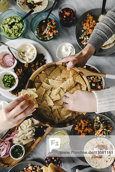 Draufsicht auf Freunde  die während des geselligen Beisammenseins Nacho-Chips bei Tisch essen