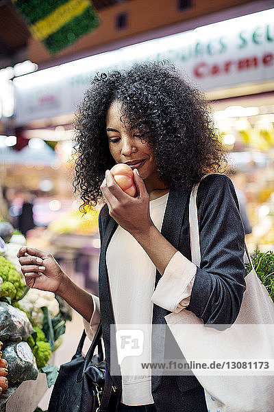 Woman examining tomato at market stall