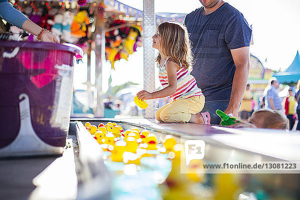 Vater mit Tochter hält Gummiente beim Vergnügen im Vergnügungspark