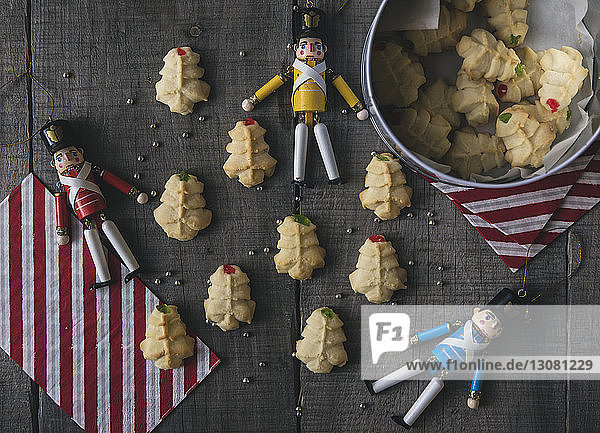 Overhead view of figurines with cookies on wooden table during Christmas