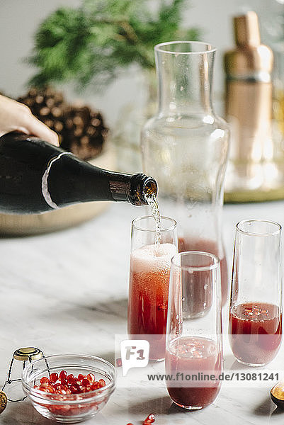 Cropped image of woman pouring champagne in juice
