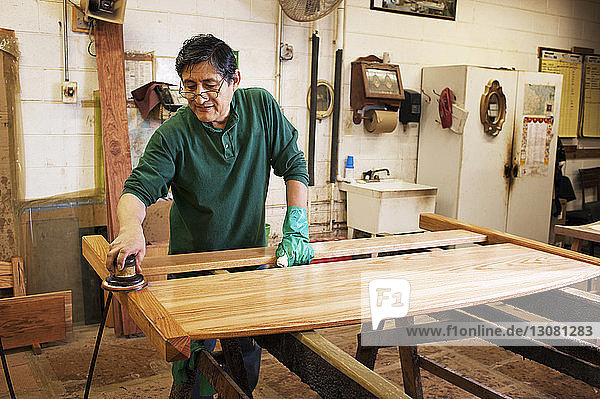 Zimmermann schleift Holzbohlen in der Werkstatt