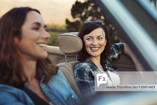 Happy female friends traveling in convertible car