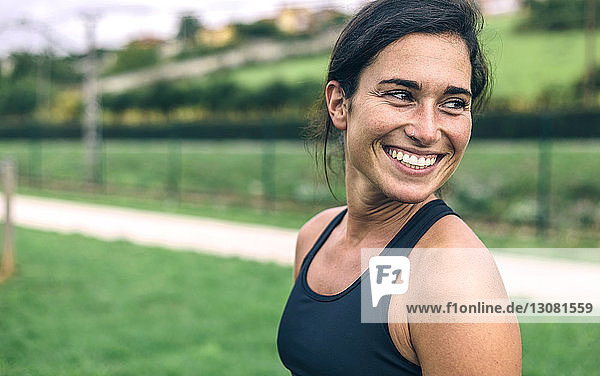 Glückliche Sportlerin schaut weg  während sie im Park trainiert