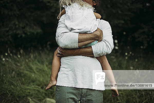 Mitten im Grasfeld: Vater umarmt Tochter