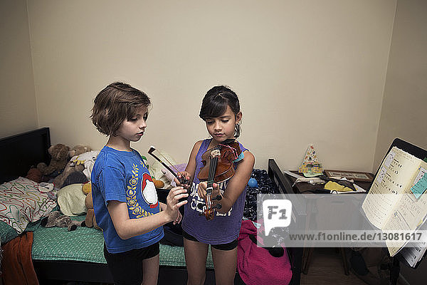 Schwestern spielen Geige im Schlafzimmer