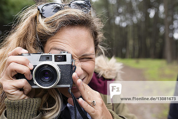 Nahaufnahme einer Frau  die durch eine Kamera im Wald fotografiert