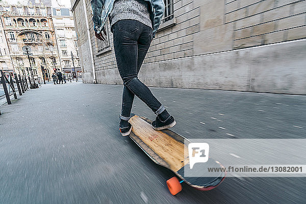 Niedriger Abschnitt einer Frau beim Skateboarden auf einem Fußweg in der Stadt