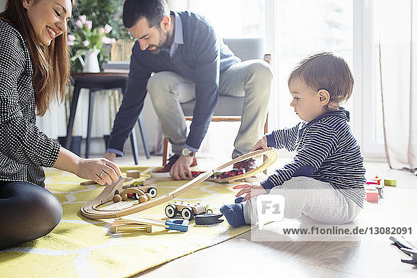 Eltern helfen Sohn beim Bau einer Spielzeugeisenbahn zu Hause