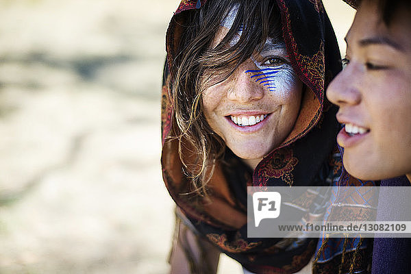 Lächelnde Freunde mit Gesichtsbemalung sprechen während der traditionellen Veranstaltung